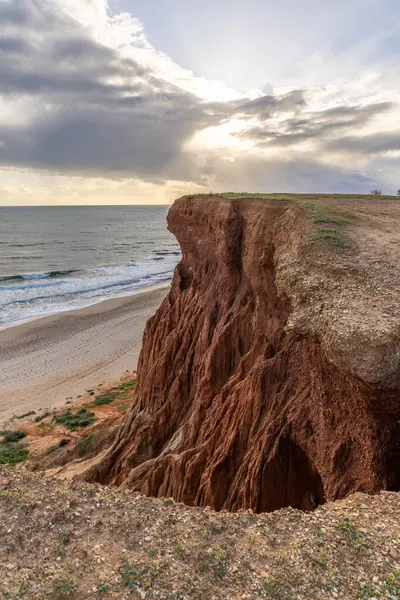 Atlantik Okyanusu 'nda çarpıcı oluşumları olan kayalıklar. Manzara çekiminde sıcak gün batımı. Sahilde ve denizde çarpıcı oluşumlara sahip kızıl kayalıklar, Praia da Falsia, Algarve, Portekiz