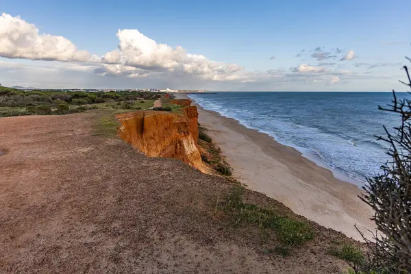 Atlantik Okyanusu 'nda çarpıcı oluşumları olan kayalıklar. Manzara çekiminde sıcak gün batımı. Sahilde ve denizde çarpıcı oluşumlara sahip kızıl kayalıklar, Praia da Falsia, Algarve, Portekiz