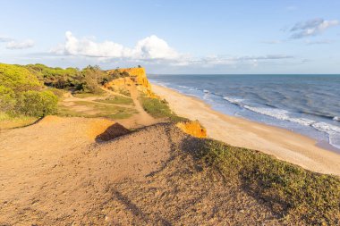 Atlantik Okyanusu 'nda çarpıcı oluşumları olan kayalıklar. Manzara çekiminde sıcak gün batımı. Sahilde ve denizde çarpıcı oluşumlara sahip kızıl kayalıklar, Praia da Falsia, Algarve, Portekiz