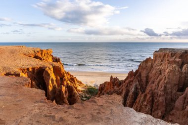 Atlantik Okyanusu 'nda çarpıcı oluşumları olan kayalıklar. Manzara çekiminde sıcak gün batımı. Sahilde ve denizde çarpıcı oluşumlara sahip kızıl kayalıklar, Praia da Falsia, Algarve, Portekiz