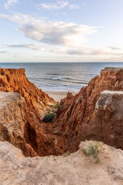 Atlantik Okyanusu 'nda çarpıcı oluşumları olan kayalıklar. Manzara çekiminde sıcak gün batımı. Sahilde ve denizde çarpıcı oluşumlara sahip kızıl kayalıklar, Praia da Falsia, Algarve, Portekiz
