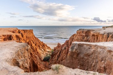 Atlantik Okyanusu 'nda çarpıcı oluşumları olan kayalıklar. Manzara çekiminde sıcak gün batımı. Sahilde ve denizde çarpıcı oluşumlara sahip kızıl kayalıklar, Praia da Falsia, Algarve, Portekiz