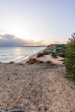 Atlantik Okyanusu 'nda çarpıcı oluşumları olan kayalıklar. Manzara çekiminde sıcak gün batımı. Sahilde ve denizde çarpıcı oluşumlara sahip kızıl kayalıklar, Praia da Falsia, Algarve, Portekiz