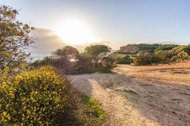 Atlantik Okyanusu 'nda çarpıcı oluşumları olan kayalıklar. Manzara çekiminde sıcak gün batımı. Sahilde ve denizde çarpıcı oluşumlara sahip kızıl kayalıklar, Praia da Falsia, Algarve, Portekiz