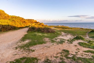 Atlantik Okyanusu 'nda çarpıcı oluşumları olan kayalıklar. Manzara çekiminde sıcak gün batımı. Sahilde ve denizde çarpıcı oluşumlara sahip kızıl kayalıklar, Praia da Falsia, Algarve, Portekiz
