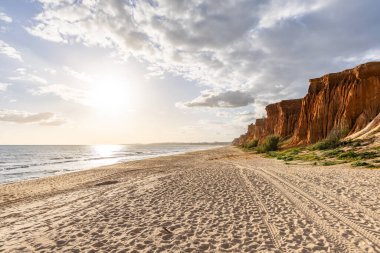 Okyanus kıyısında inanılmaz bir kaya oluşumu. Kızıl toprağı ve geniş kumsalda çarpıcı oluşumları olan kızıl kayalıklar. Praia da Falsia, güneş batarken sıcak bir ışıkta yıkandı, Algarve, Portekiz
