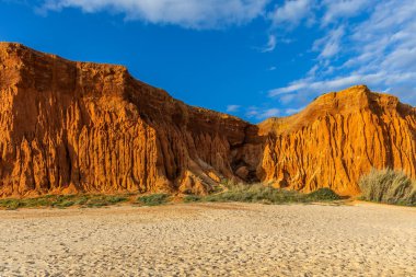 Bir çakıl taşı ve kumsalda inanılmaz kaya oluşumu. Kızıl topraklı kızıl kayalıklar ve kumlu sahilde inanılmaz oluşumlar. Praia da Falsia, sıcak güneş ışığıyla yıkanmış, Algarve, Portekiz
