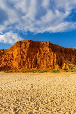 Bir çakıl taşı ve kumsalda inanılmaz kaya oluşumu. Kızıl topraklı kızıl kayalıklar ve kumlu sahilde inanılmaz oluşumlar. Praia da Falsia, sıcak güneş ışığıyla yıkanmış, Algarve, Portekiz