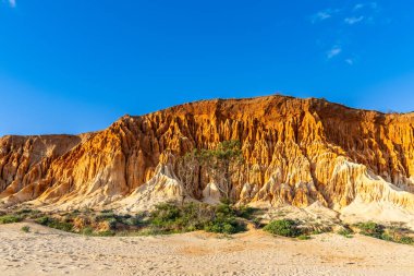 Bir çakıl taşı ve kumsalda inanılmaz kaya oluşumu. Kızıl topraklı kızıl kayalıklar ve kumlu sahilde inanılmaz oluşumlar. Praia da Falsia, sıcak güneş ışığıyla yıkanmış, Algarve, Portekiz