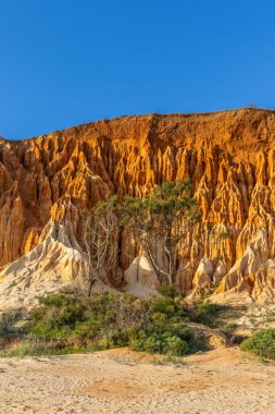 Bir çakıl taşı ve kumsalda inanılmaz kaya oluşumu. Kızıl topraklı kızıl kayalıklar ve kumlu sahilde inanılmaz oluşumlar. Praia da Falsia, sıcak güneş ışığıyla yıkanmış, Algarve, Portekiz