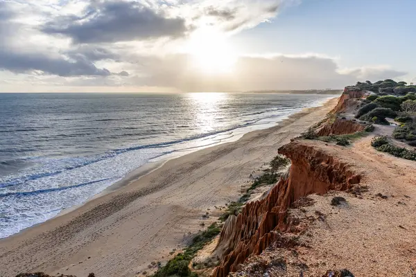 Atlantik Okyanusu 'nda çarpıcı oluşumları olan kayalıklar. Manzara çekiminde sıcak gün batımı. Sahilde ve denizde çarpıcı oluşumlara sahip kızıl kayalıklar, Praia da Falsia, Algarve, Portekiz