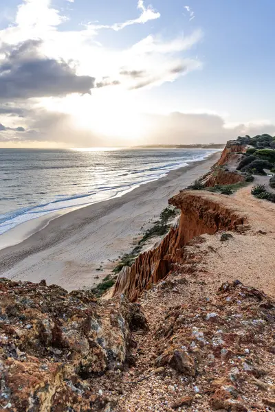 Atlantik Okyanusu 'nda çarpıcı oluşumları olan kayalıklar. Manzara çekiminde sıcak gün batımı. Sahilde ve denizde çarpıcı oluşumlara sahip kızıl kayalıklar, Praia da Falsia, Algarve, Portekiz