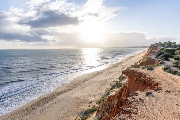 Atlantik Okyanusu 'nda çarpıcı oluşumları olan kayalıklar. Manzara çekiminde sıcak gün batımı. Sahilde ve denizde çarpıcı oluşumlara sahip kızıl kayalıklar, Praia da Falsia, Algarve, Portekiz