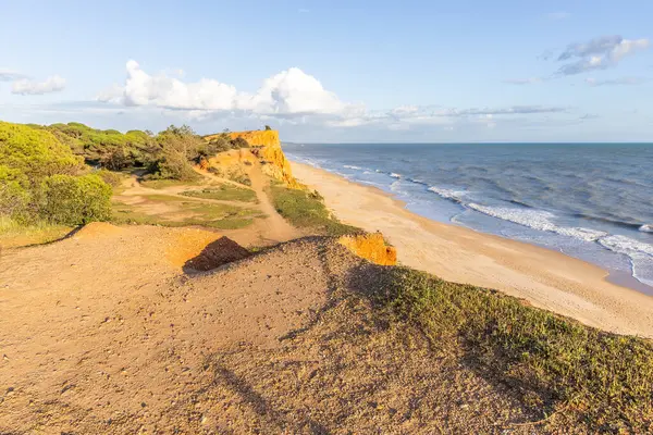 Atlantik Okyanusu 'nda çarpıcı oluşumları olan kayalıklar. Manzara çekiminde sıcak gün batımı. Sahilde ve denizde çarpıcı oluşumlara sahip kızıl kayalıklar, Praia da Falsia, Algarve, Portekiz