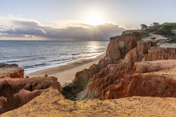 Atlantik Okyanusu 'nda çarpıcı oluşumları olan kayalıklar. Manzara çekiminde sıcak gün batımı. Sahilde ve denizde çarpıcı oluşumlara sahip kızıl kayalıklar, Praia da Falsia, Algarve, Portekiz