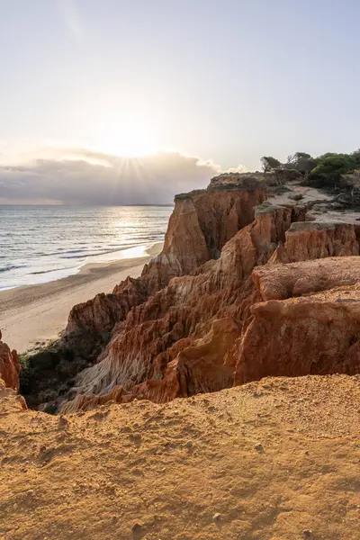 Atlantik Okyanusu 'nda çarpıcı oluşumları olan kayalıklar. Manzara çekiminde sıcak gün batımı. Sahilde ve denizde çarpıcı oluşumlara sahip kızıl kayalıklar, Praia da Falsia, Algarve, Portekiz