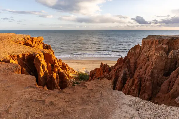 Atlantik Okyanusu 'nda çarpıcı oluşumları olan kayalıklar. Manzara çekiminde sıcak gün batımı. Sahilde ve denizde çarpıcı oluşumlara sahip kızıl kayalıklar, Praia da Falsia, Algarve, Portekiz