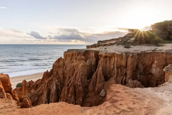 Atlantik Okyanusu 'nda çarpıcı oluşumları olan kayalıklar. Manzara çekiminde sıcak gün batımı. Sahilde ve denizde çarpıcı oluşumlara sahip kızıl kayalıklar, Praia da Falsia, Algarve, Portekiz