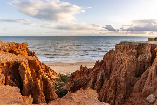 Atlantik Okyanusu 'nda çarpıcı oluşumları olan kayalıklar. Manzara çekiminde sıcak gün batımı. Sahilde ve denizde çarpıcı oluşumlara sahip kızıl kayalıklar, Praia da Falsia, Algarve, Portekiz