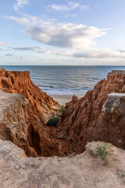 Atlantik Okyanusu 'nda çarpıcı oluşumları olan kayalıklar. Manzara çekiminde sıcak gün batımı. Sahilde ve denizde çarpıcı oluşumlara sahip kızıl kayalıklar, Praia da Falsia, Algarve, Portekiz