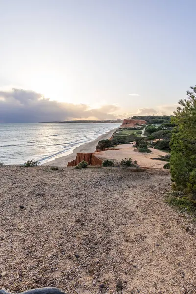 Atlantik Okyanusu 'nda çarpıcı oluşumları olan kayalıklar. Manzara çekiminde sıcak gün batımı. Sahilde ve denizde çarpıcı oluşumlara sahip kızıl kayalıklar, Praia da Falsia, Algarve, Portekiz