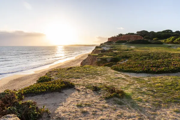 Atlantik Okyanusu 'nda çarpıcı oluşumları olan kayalıklar. Manzara çekiminde sıcak gün batımı. Sahilde ve denizde çarpıcı oluşumlara sahip kızıl kayalıklar, Praia da Falsia, Algarve, Portekiz