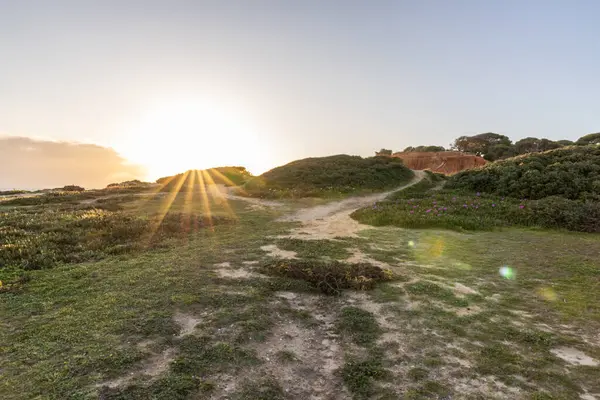Atlantik Okyanusu 'nda çarpıcı oluşumları olan kayalıklar. Manzara çekiminde sıcak gün batımı. Sahilde ve denizde çarpıcı oluşumlara sahip kızıl kayalıklar, Praia da Falsia, Algarve, Portekiz