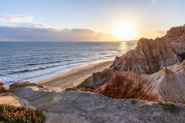 Atlantik Okyanusu 'nda çarpıcı oluşumları olan kayalıklar. Manzara çekiminde sıcak gün batımı. Sahilde ve denizde çarpıcı oluşumlara sahip kızıl kayalıklar, Praia da Falsia, Algarve, Portekiz