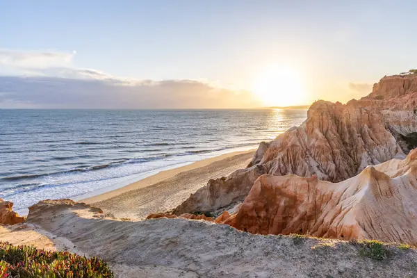 Atlantik Okyanusu 'nda çarpıcı oluşumları olan kayalıklar. Manzara çekiminde sıcak gün batımı. Sahilde ve denizde çarpıcı oluşumlara sahip kızıl kayalıklar, Praia da Falsia, Algarve, Portekiz