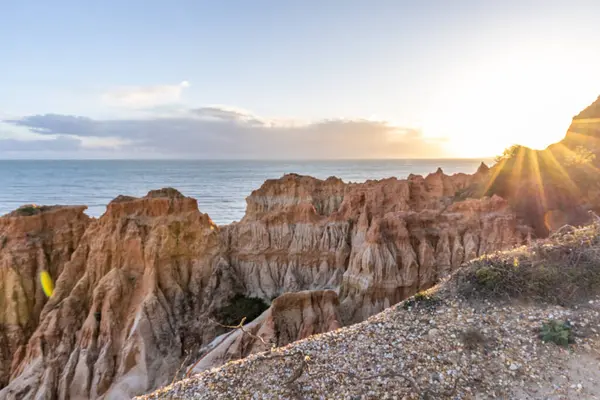 Atlantik Okyanusu 'nda çarpıcı oluşumları olan kayalıklar. Manzara çekiminde sıcak gün batımı. Sahilde ve denizde çarpıcı oluşumlara sahip kızıl kayalıklar, Praia da Falsia, Algarve, Portekiz