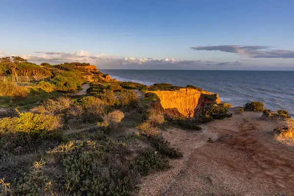 Atlantik Okyanusu 'nda çarpıcı oluşumları olan kayalıklar. Manzara çekiminde sıcak gün batımı. Sahilde ve denizde çarpıcı oluşumlara sahip kızıl kayalıklar, Praia da Falsia, Algarve, Portekiz