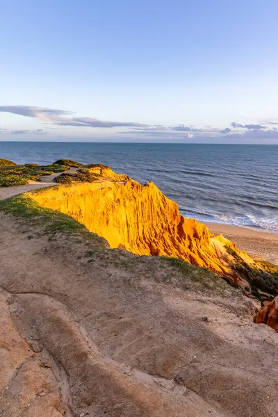 Atlantik Okyanusu 'nda çarpıcı oluşumları olan kayalıklar. Manzara çekiminde sıcak gün batımı. Sahilde ve denizde çarpıcı oluşumlara sahip kızıl kayalıklar, Praia da Falsia, Algarve, Portekiz