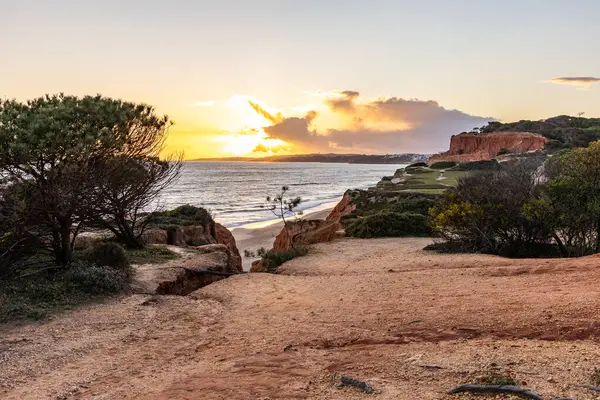 Atlantik Okyanusu 'nda çarpıcı oluşumları olan kayalıklar. Manzara çekiminde sıcak gün batımı. Sahilde ve denizde çarpıcı oluşumlara sahip kızıl kayalıklar, Praia da Falsia, Algarve, Portekiz