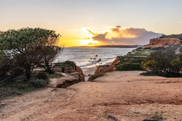 Atlantik Okyanusu 'nda çarpıcı oluşumları olan kayalıklar. Manzara çekiminde sıcak gün batımı. Sahilde ve denizde çarpıcı oluşumlara sahip kızıl kayalıklar, Praia da Falsia, Algarve, Portekiz