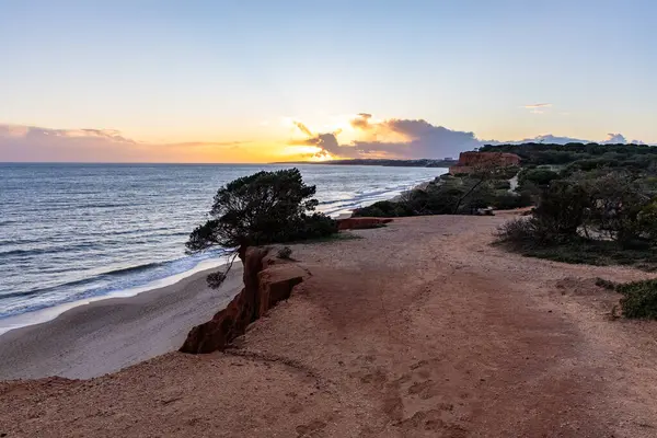 Atlantik Okyanusu 'nda çarpıcı oluşumları olan kayalıklar. Manzara çekiminde sıcak gün batımı. Sahilde ve denizde çarpıcı oluşumlara sahip kızıl kayalıklar, Praia da Falsia, Algarve, Portekiz