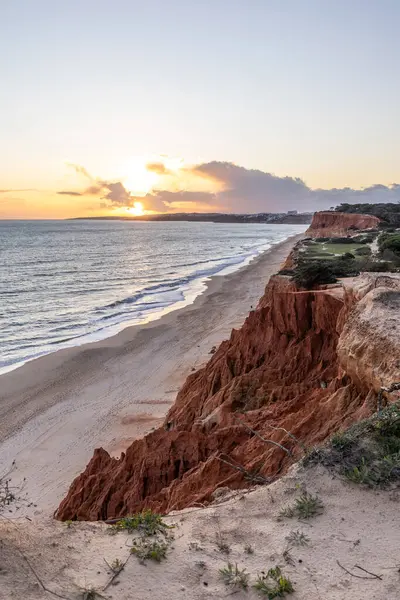Atlantik Okyanusu 'nda çarpıcı oluşumları olan kayalıklar. Manzara çekiminde sıcak gün batımı. Sahilde ve denizde çarpıcı oluşumlara sahip kızıl kayalıklar, Praia da Falsia, Algarve, Portekiz
