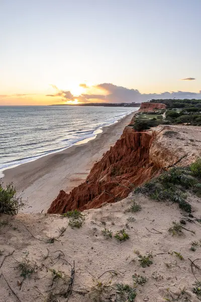 Atlantik Okyanusu 'nda çarpıcı oluşumları olan kayalıklar. Manzara çekiminde sıcak gün batımı. Sahilde ve denizde çarpıcı oluşumlara sahip kızıl kayalıklar, Praia da Falsia, Algarve, Portekiz