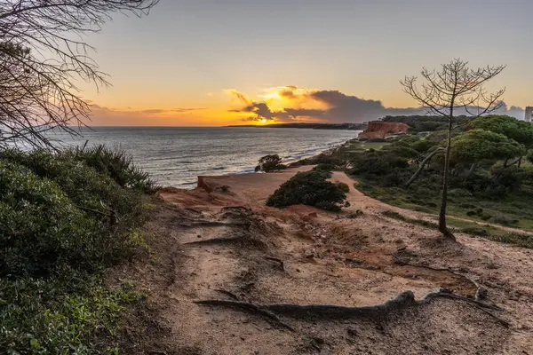 Atlantik Okyanusu 'nda çarpıcı oluşumları olan kayalıklar. Manzara çekiminde sıcak gün batımı. Sahilde ve denizde çarpıcı oluşumlara sahip kızıl kayalıklar, Praia da Falsia, Algarve, Portekiz