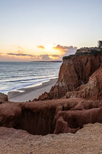 Atlantik Okyanusu 'nda çarpıcı oluşumları olan kayalıklar. Manzara çekiminde sıcak gün batımı. Sahilde ve denizde çarpıcı oluşumlara sahip kızıl kayalıklar, Praia da Falsia, Algarve, Portekiz