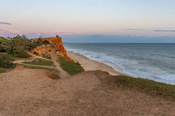 Atlantik Okyanusu 'nda çarpıcı oluşumları olan kayalıklar. Manzara çekiminde sıcak gün batımı. Sahilde ve denizde çarpıcı oluşumlara sahip kızıl kayalıklar, Praia da Falsia, Algarve, Portekiz
