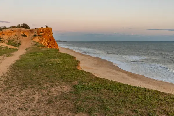 Atlantik Okyanusu 'nda çarpıcı oluşumları olan kayalıklar. Manzara çekiminde sıcak gün batımı. Sahilde ve denizde çarpıcı oluşumlara sahip kızıl kayalıklar, Praia da Falsia, Algarve, Portekiz