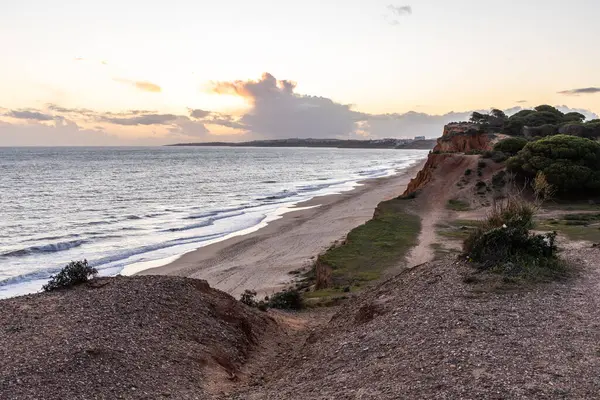 Atlantik Okyanusu 'nda çarpıcı oluşumları olan kayalıklar. Manzara çekiminde sıcak gün batımı. Sahilde ve denizde çarpıcı oluşumlara sahip kızıl kayalıklar, Praia da Falsia, Algarve, Portekiz