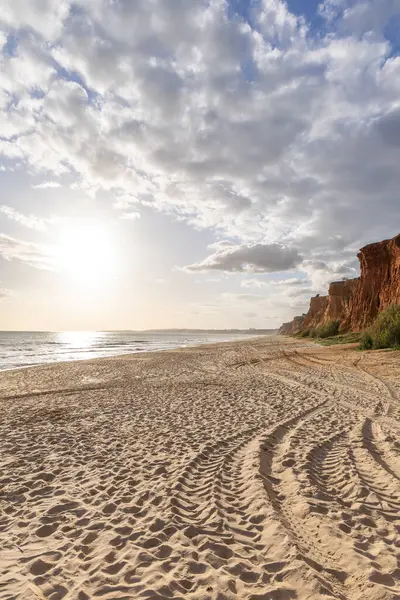 Okyanus kıyısında inanılmaz bir kaya oluşumu. Kızıl toprağı ve geniş kumsalda çarpıcı oluşumları olan kızıl kayalıklar. Praia da Falsia, güneş batarken sıcak bir ışıkta yıkandı, Algarve, Portekiz