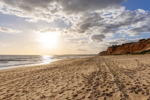 Okyanus kıyısında inanılmaz bir kaya oluşumu. Kızıl toprağı ve geniş kumsalda çarpıcı oluşumları olan kızıl kayalıklar. Praia da Falsia, güneş batarken sıcak bir ışıkta yıkandı, Algarve, Portekiz