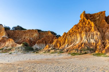 Bir çakıl taşı ve kumsalda inanılmaz kaya oluşumu. Kızıl topraklı kızıl kayalıklar ve kumlu sahilde inanılmaz oluşumlar. Praia da Falsia, sıcak güneş ışığıyla yıkanmış, Algarve, Portekiz