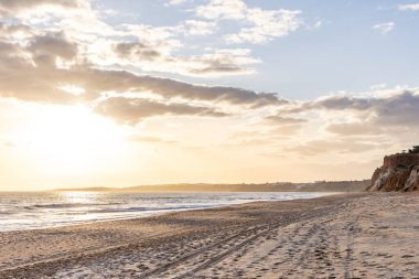 Okyanus kıyısında inanılmaz bir kaya oluşumu. Kızıl toprağı ve geniş kumsalda çarpıcı oluşumları olan kızıl kayalıklar. Praia da Falsia, güneş batarken sıcak bir ışıkta yıkandı, Algarve, Portekiz