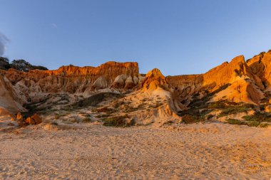 Bir çakıl taşı ve kumsalda inanılmaz kaya oluşumu. Kızıl topraklı kızıl kayalıklar ve kumlu sahilde inanılmaz oluşumlar. Praia da Falsia, sıcak güneş ışığıyla yıkanmış, Algarve, Portekiz