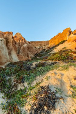 Bir çakıl taşı ve kumsalda inanılmaz kaya oluşumu. Kızıl topraklı kızıl kayalıklar ve kumlu sahilde inanılmaz oluşumlar. Praia da Falsia, sıcak güneş ışığıyla yıkanmış, Algarve, Portekiz
