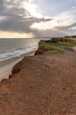 Atlantik Okyanusu 'nda çarpıcı oluşumları olan kayalıklar. Manzara çekiminde sıcak gün batımı. Sahilde ve denizde çarpıcı oluşumlara sahip kızıl kayalıklar, Praia da Falsia, Algarve, Portekiz