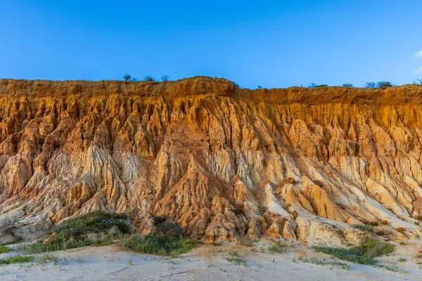 Bir çakıl taşı ve kumsalda inanılmaz kaya oluşumu. Kızıl topraklı kızıl kayalıklar ve kumlu sahilde inanılmaz oluşumlar. Praia da Falsia, sıcak güneş ışığıyla yıkanmış, Algarve, Portekiz